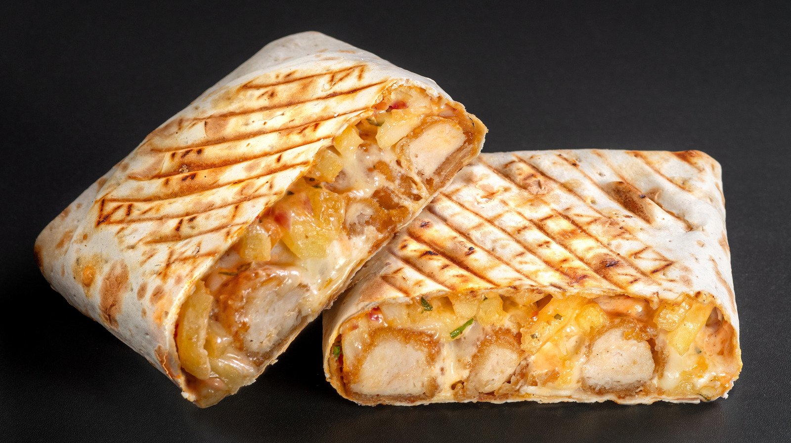 French tacos with chicken popcorn. Served with french fries on a black background French tacos with chicken popcorn. Cut French Tacos close up on black background. Delicious french taco sandwich fastfood nice good amazing food